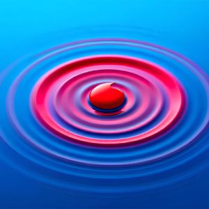 Red droplet creating concentric ripples in blue water, symbolizing the ripple effect of impactful decisions, innovation, and global influence in business or technology.