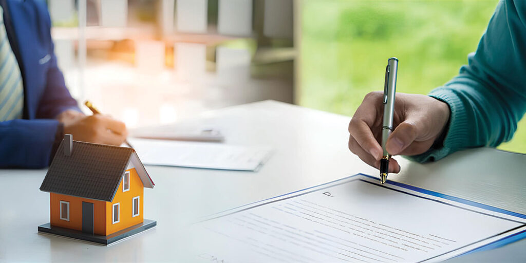 Close-up of a person signing real estate documents beside a miniature house model, representing property investment agreements, mortgage deals, and developer opportunities in the GCC and MENA markets.
